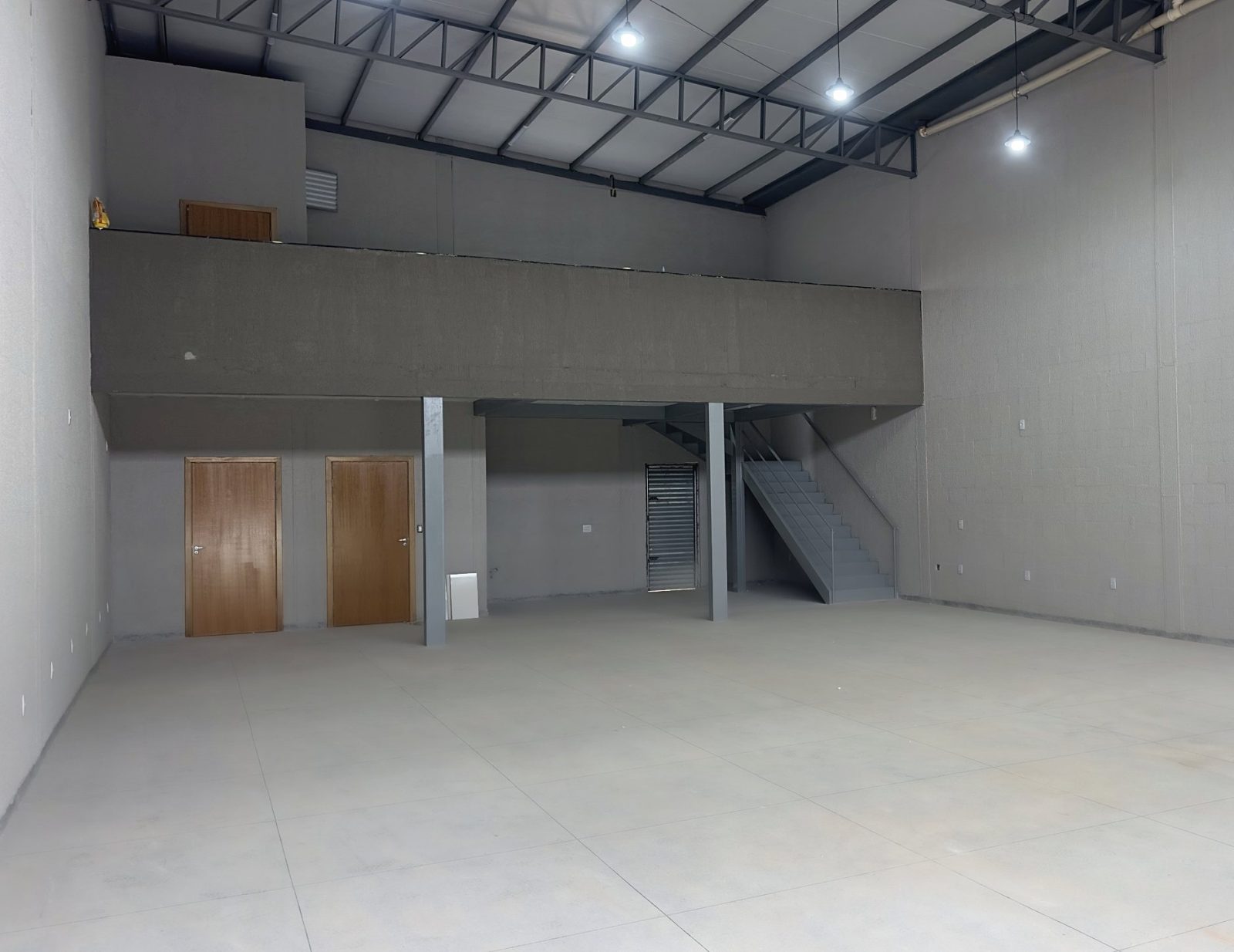Interior de galpão pronto com mezanino, escada metálica e piso de concreto