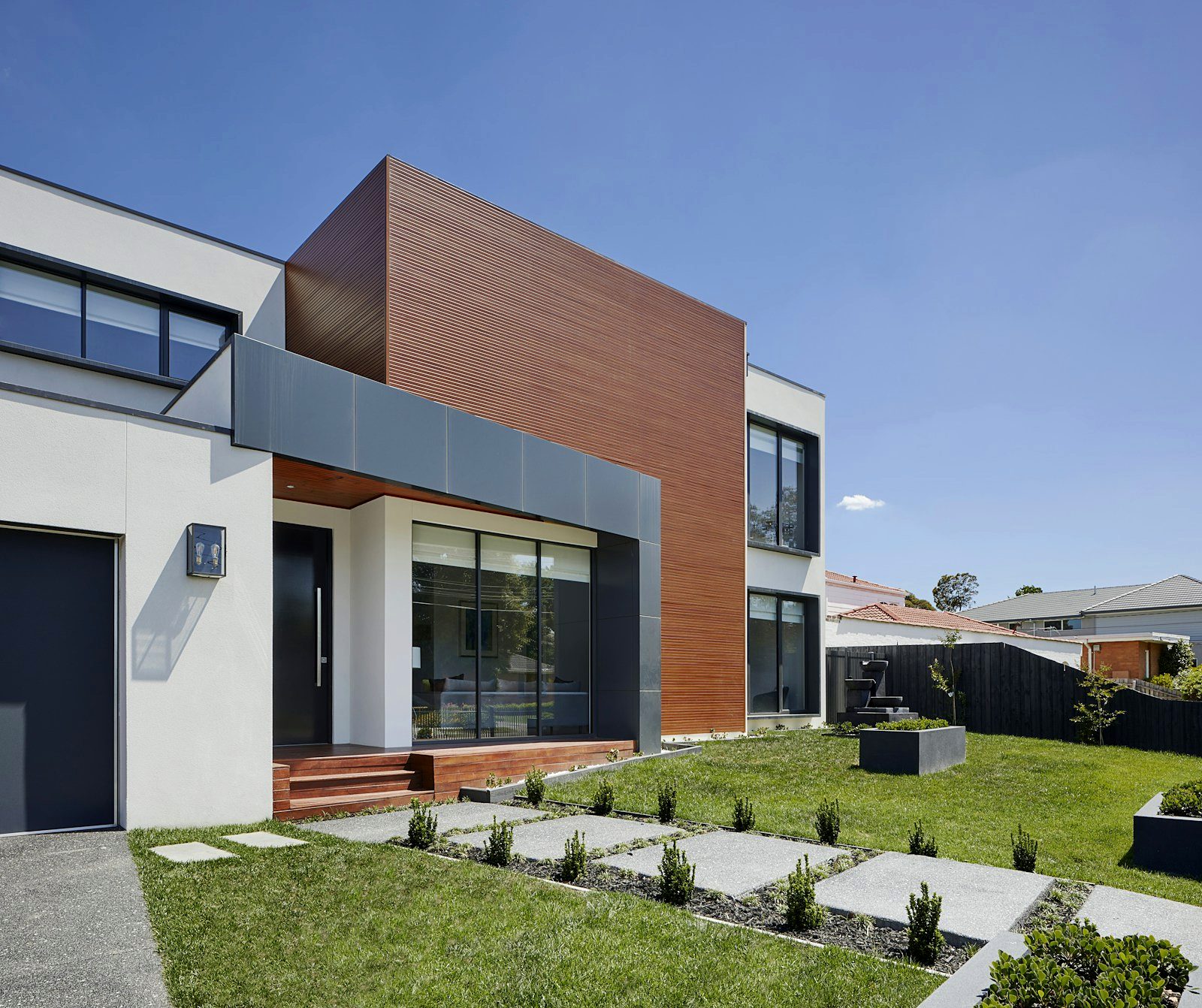 Casa contemporânea com fachada branca e revestimento de madeira